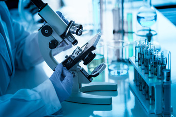 Micorscope is used by researcher who use her hands holding and adjusting