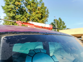 windscreen is being replacing and silicone bottle is kept on the roof top of a red vehicle  