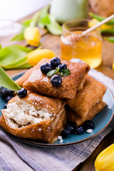 Large traditional Russian pancakes with berries and honey on a wooden table. Baking for the spring holiday Shrovetide and a bouquet of yellow tulips. Copy space