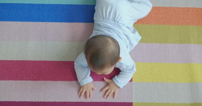 Asian baby crawing on floor in living room, top view. Childhood and nursery service concept.