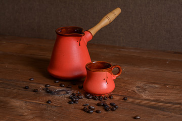 Ceramic cup, cezve for coffee, coffee grains on a wooden table.