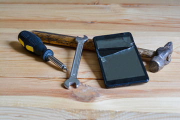 Broken phone screen, hammer, screwdriver and wrench
