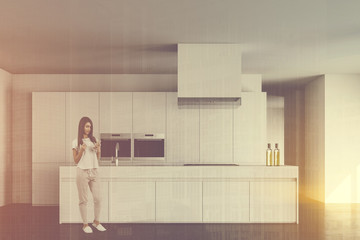 Young woman in white kitchen with island