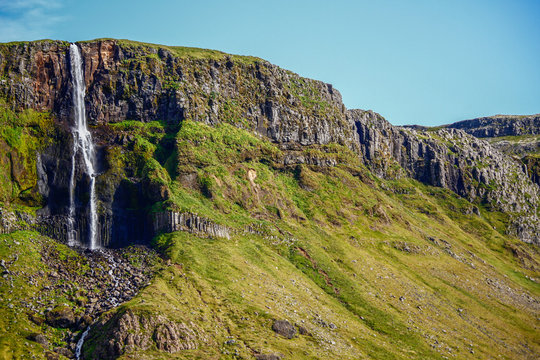 Landschaft der Halbinsel Snaefellsnes mit gr&uuml;nen Bergen und Wasserfall im Westen von Island