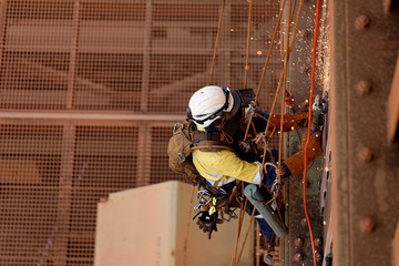 Tope view of rope access technician welder services wearing white helmet head fall protection PPE,...