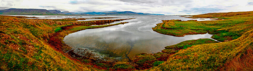 Obraz premium Panorama der weiten Fjordlandschaft mit Meer, Bergen, bunten Moosen und Wolken im Norden von Island, den Westfjorden 