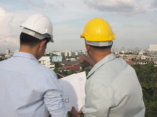  asian male engineer or foreman and male architects Asian people discussing blueprint of future building or check documents and business workflow.