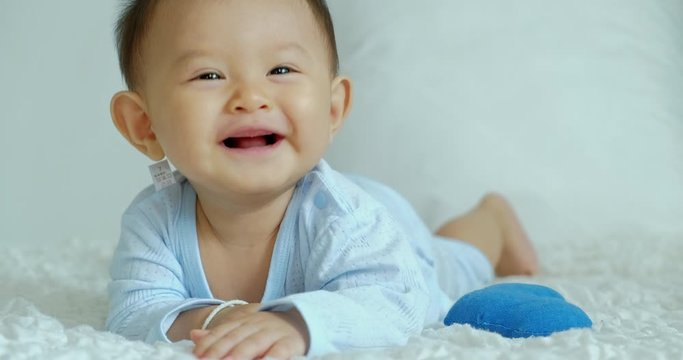 Close up of Smile and laugh happy baby laying in bed with copy space. Asian baby boy.