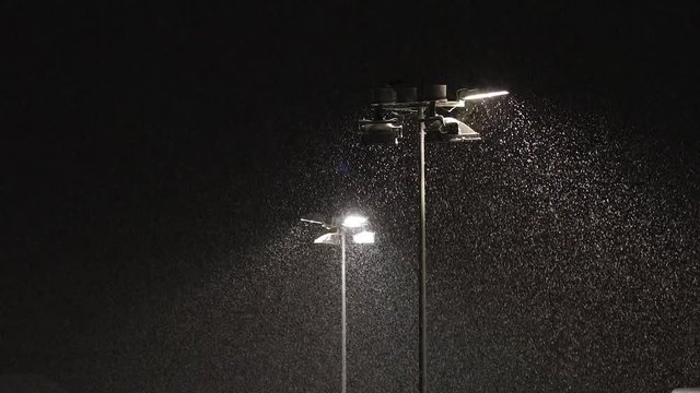 Winter snowfall in the night embraced with stadion lights on the right in slow motion