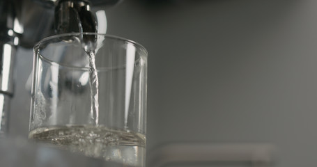 low angle water pour from coffee machine into glass