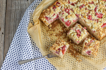 strawberry rhubarb crumble cake on blue brindle plate on a baking paper