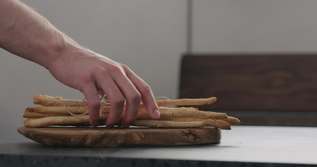 man hand take bunch of homemade grissini from olive board