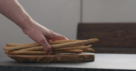 man hand put bunch of homemade grissini on olive board