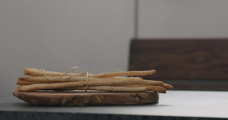 bunch of homemade grissini on olive board on concrete countertop