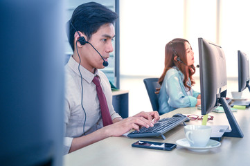 Young customer service men agent with headsets and computer working at office.
