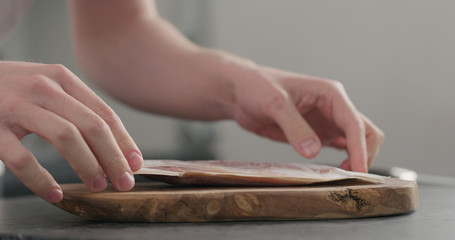 man unpack prosciutto on olive board