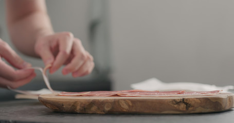 man unpack prosciutto on olive board