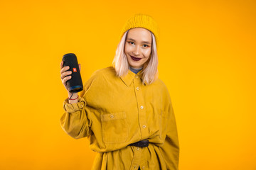 Modern trendy girl listening to music by wireless portable speaker.