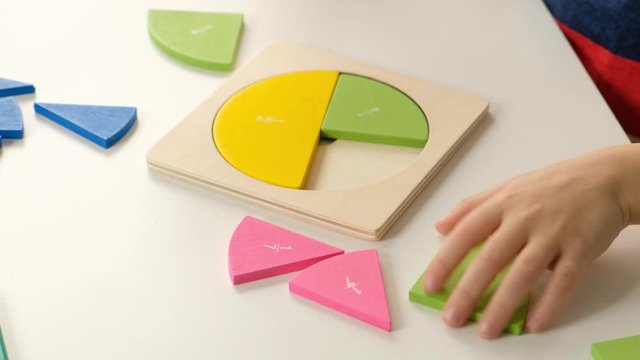 Child hand doing simple math exercises with fractions on white table, close up. dividing fractions