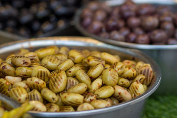 A pile of green pickled olives, oil-coated and grilled. In a metal bowl. Blurred background. Arabic style. The Old Market, Jerusalem.