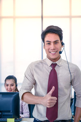 Young customer service men agent Thumbs up with headsets and computer working at office.