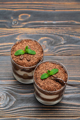 Classic tiramisu dessert in a glass cup on wooden background