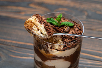 Classic tiramisu dessert in a glass cup on wooden background