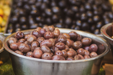 A pile of shiny Syrian brown olives and full of oil. Inside a metal bowl. Arabic style. The Old Market of Mahane Yehuda, Jerusalem.