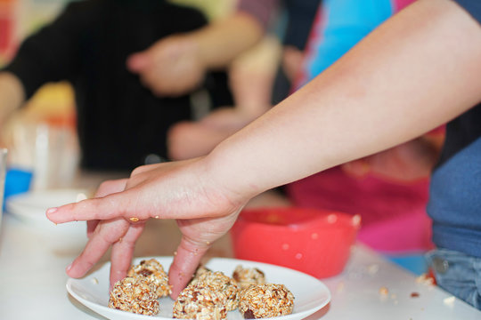 Children's Hands Making Balls Of Oats With Raisins And Almonds And Honey. Children Make Sweets. Kids Cooking. Concept. Master Class For Children On Healthy Eating Habits.