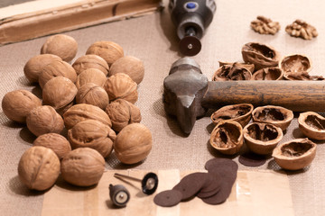 A tool, hammer and electric engraver for opening walnuts and creating exclusive products from the shell are laid out on the desktop.