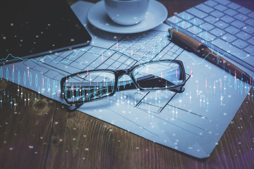 Financial chart hologram with glasses on the table background. Concept of business. Double exposure.