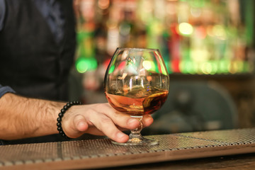 hand holding a glass of whiskey at the bar