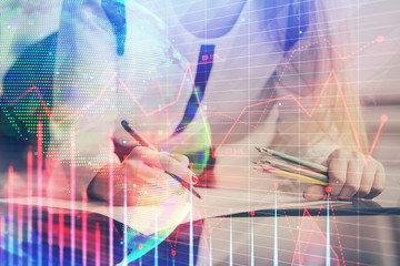 Double exposure of hands making notes with forex chart huds. Stock market concept.