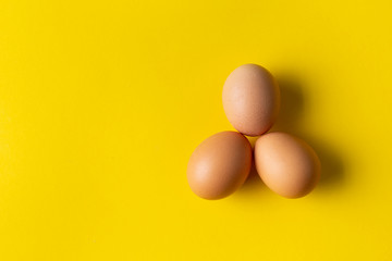 Three eggs on yellow background.