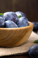 Ripe plums in a wooden bowl. Fresh fruits.