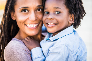 Portrait of family couple mother and son black afro ethnic race smile and look at the camera - concept of diversity and single mom with young children - happiness and joy concept with love 