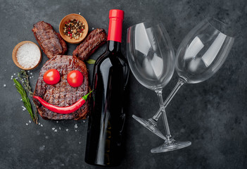 Grilled Easter steak with spices and a bottle of wine and glasses, multi-colored eggs Easter bunny on a stone background with copy space for your text.