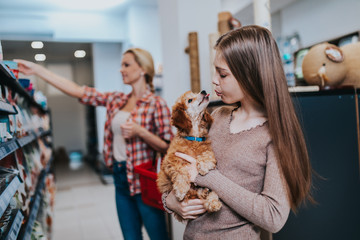 Mother and daughter with their poodle puppy in pet shop.