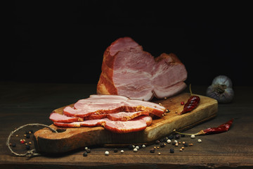 Sliced smoked pork meat with spices lies on an ancient cutting Board on a wooden rustic table...