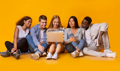 International group of teenagers looking at laptop screen