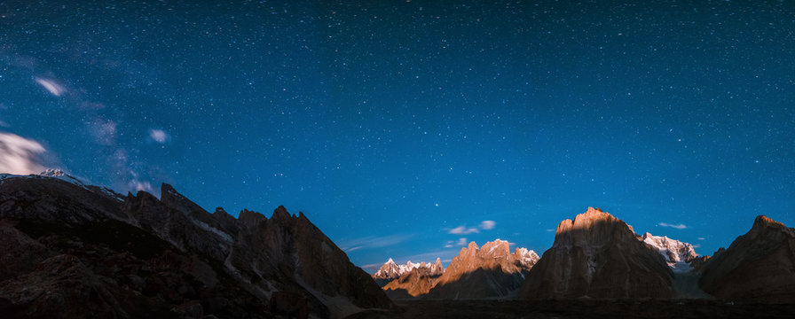 Starry night panoramic view of Baltoro Glacier and milky way behind Urdukas with Paiju, Uli Biaho, Great Trango Peak, Main Cathedral, Pakistan
