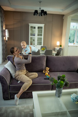 Obraz premium Smiling young beautiful lady resting with her kid at home