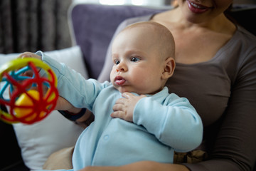 Pretty young woman with her cute baby playing on a sofa