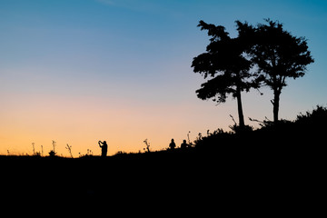 Fototapeta na wymiar Silhouettes of people walking over the hill in beautiful colorful sunset. Outdoor activities