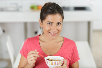 beautiful woman eating cereals in kitchen for breakfast