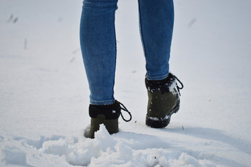 Winter woman shoes covered with snow and walking in the snow during winter