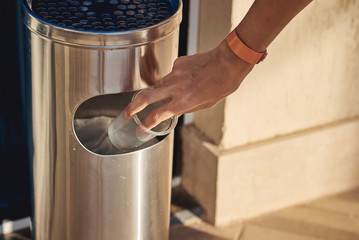 Woman hand throwing plactic cup for water in a trash bin
