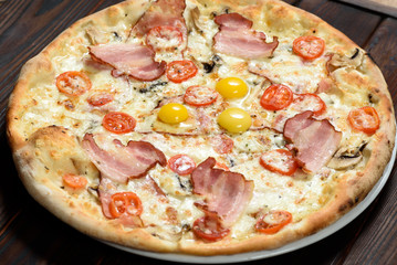 Tasty pizza with cheese, quail eggs, spices and tomatoes