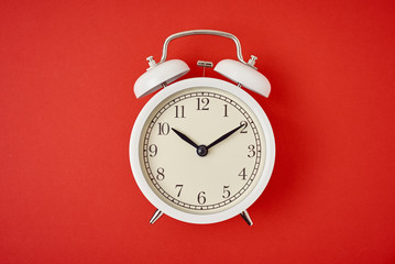 White retro alarm clock on the red background with copy space. Time concept