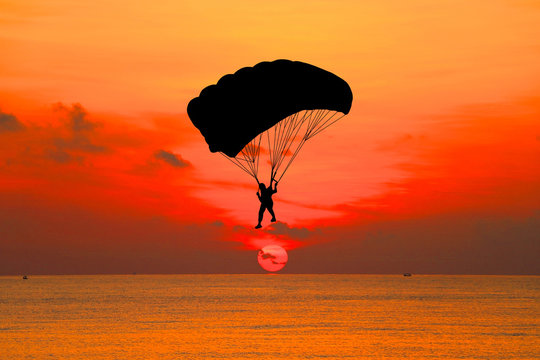 Silhouette Skydiver In Sky On  Sunrise